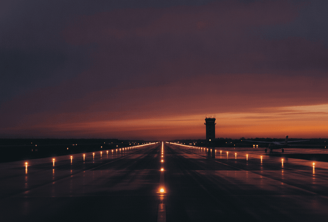 Regional airport runway edge lights at dusk with control tower silhouette
